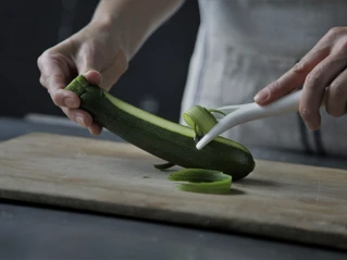 Bild på händer som skalar en zucchini